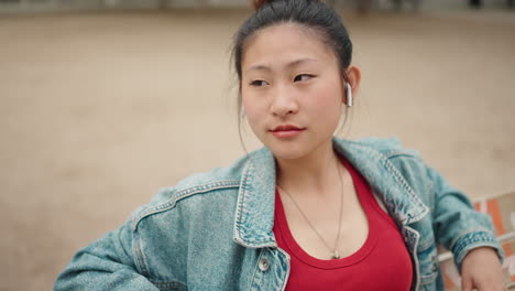 Asian-woman-with-wireless-earphones-in-the-park.