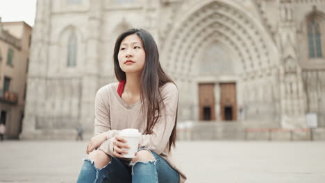 Chica-Asiática-Vestida-Informalmente-Esperando-A-Un-Amigo-Al-Aire-Libre-Con-Café-Para-Llevar.