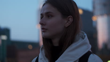 Close-up-shot-of-Caucasian-girl-happily-walking-alone-through-evening-street.