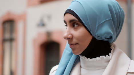 Close-up-shot-of-young-Arabian-woman-dreamily-looking-away-walking-through-city-street.