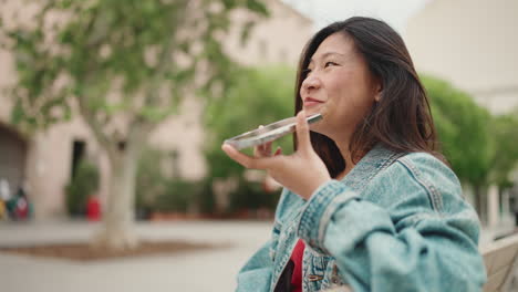 Asiatische-Frau-Nimmt-Auf-Einer-Bank-Im-Park-Eine-Audioaufnahme-Auf.