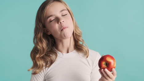 Teenage-Caucasian-girl-in-pijamas-eating-an-apple-and-smiling.