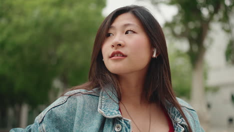 Asian-woman-with-wireless-earphones-in-the-park.