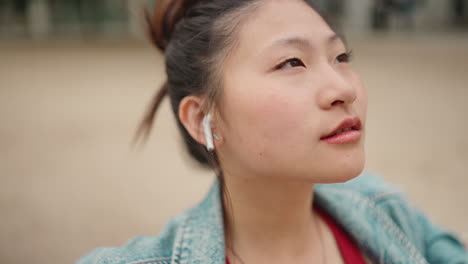 Mujer-Asiática-Con-Auriculares-Inalámbricos-En-El-Parque.