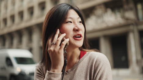 Asian-girl-talking-on-the-phone-downtown.