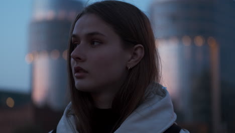 Close-up-shot-of-Caucasian-girl-thoughtfully-looking-away-on-evening-street-walking-at-dusk.