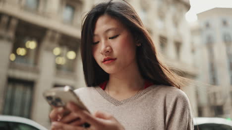 Young-Asian-woman-using-mobile-outdoors.