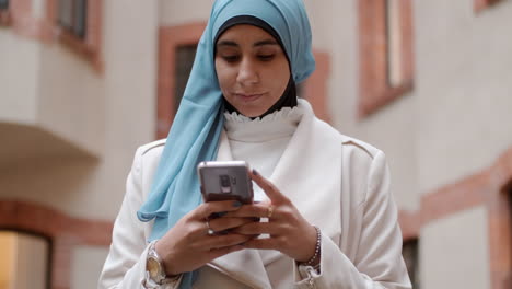 Young-pensive-Arabian-woman-thoughtfully-using-cellphone-on-city-street.