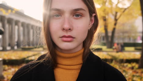 Portrait-of-Caucasian-girl-intently-looking-in-camera-in-city-park-at-sunset.