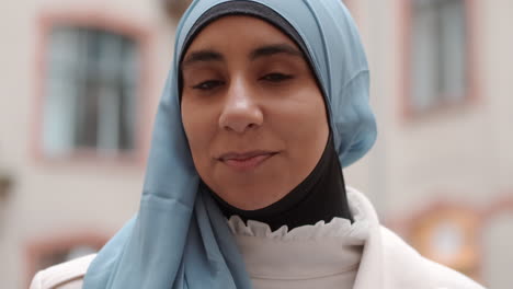 Portrait-of-young-Arabian-woman-happily-looking-in-camera-and-smiling-on-street.