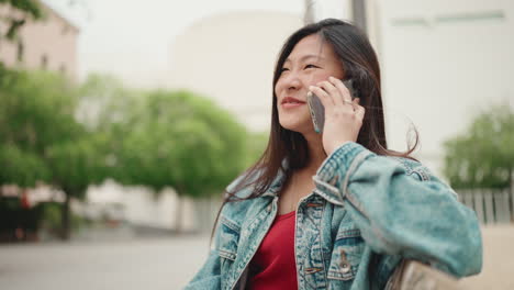 Asiatische-Frau-Ruft-Einen-Freund-Auf-Einer-Bank-Im-Park-An.