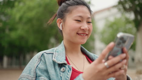 Mujer-Asiática-Con-Auriculares-Inalámbricos-En-El-Parque.