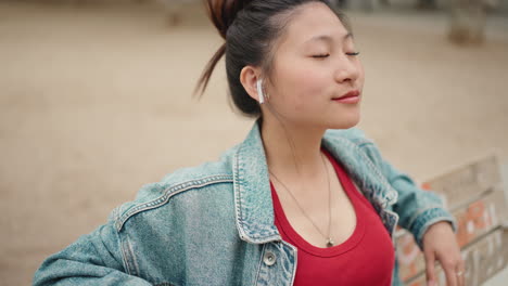 Mujer-Asiática-Con-Auriculares-Inalámbricos-En-El-Parque.