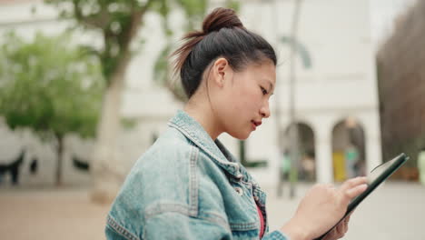 Asiatisches-Mädchen-Sitzt-Im-Park-Und-Scrollt-Auf-Ihrem-Tablet-Gerät.