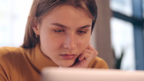 Close-up-shot-of-beautiful-smiling-student-girl-studying-on-laptop-in-cafe.