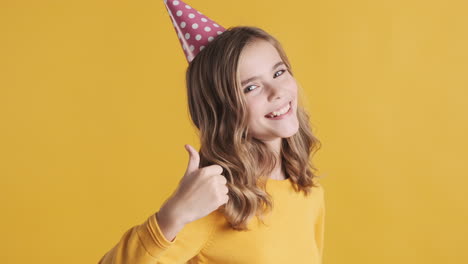 Teenage-Caucasian-girl-with-thumbs-up-wearing-a-party-hat.