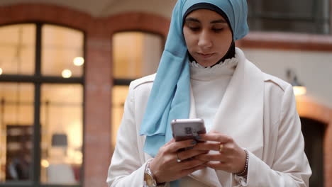 Joven-Atractiva-Mujer-árabe-Usando-Pensativamente-Su-Teléfono-Celular-En-La-Calle-De-La-Ciudad.