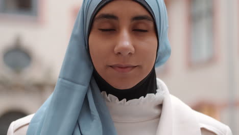 Portrait-of-young-Arabian-woman-intently-looking-in-camera-on-city-street.