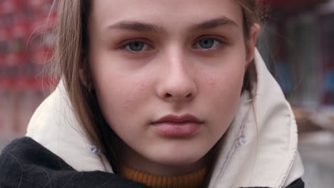 Close-up-portrait-shot-of-serious-casual-girl-in-a-jacket-with-scarf-intently-looking-in-camera-outdoor.