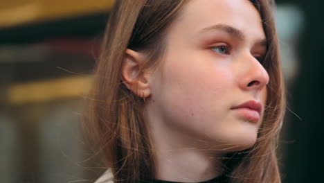 Close-up-portrait-shot-of-Caucasian-girl-looking-at-the-camera-with-train-on-background-at-subway-station.