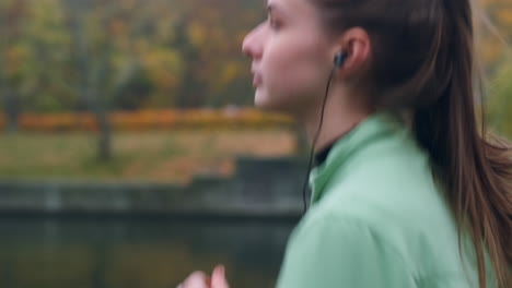 Seitenansicht-Eines-Sportlichen-Kaukasischen-Mädchens-Mit-Kopfhörern,-Das-Nachdenklich-Im-Herbstlichen-Stadtpark-Läuft.