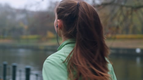 Vista-Posterior-De-Una-Chica-Deportista-Con-Auriculares-Corriendo-En-El-Parque-De-La-Ciudad-De-Otoño-Junto-Al-Río.