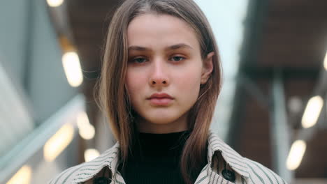 Portrait-of-confident-Caucasian-girl-intently-looking-in-camera-on-stairs-at-subway-station.