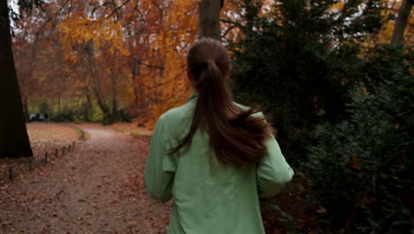 Back-view-of-sporty-Caucasian-girl-running-in-beautiful-autumn-city-park.