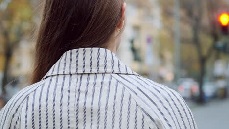 Toma-De-Vista-Posterior-De-Una-Elegante-Chica-Caucásica-Con-Abrigo-Esperando-En-El-Semáforo-En-Una-Calle-De-La-Ciudad.