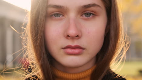 Portrait-of-beautiful-girl-opening-eyes-intently-looking-in-camera-outdoor-at-sunset.