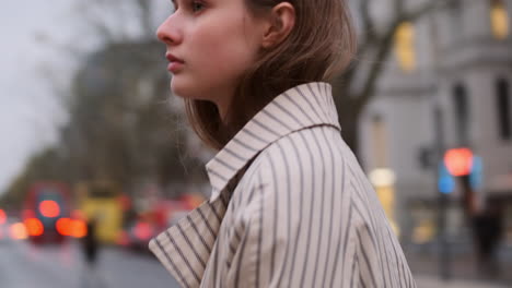 Stylish-Caucasian-girl-in-coat-thoughtfully-walking-through-rainy-city-street.