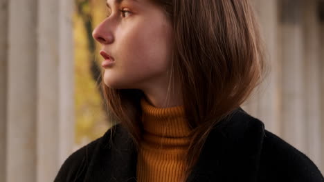 Tracking-shot-of-Caucasian-girl-in-coat-thoughtfully-looking-around-walking-in-fall-park-at-sunset.