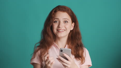 Redheaded-girl-in-front-of-camera-on-turquoise-background.