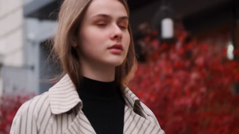 Caucasian-girl-in-trench-coat-confidently-walking-through-city-street.