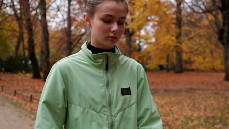 Sporty-Caucasian-girl-checking-smart-watch-after-running-in-autumn-city-park.