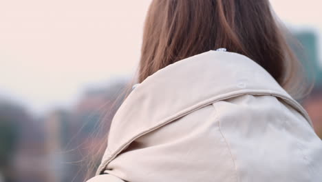 Tracking-around-shot-of-Caucasian-girl-in-down-jacket-leaning-on-hand-and-dreaming-on-city-street.