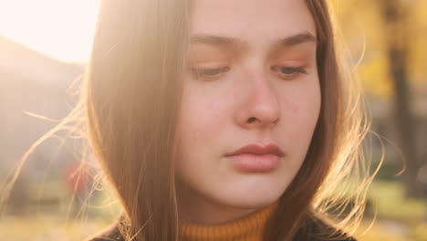 Portrait-of-Caucasian-girl-thoughtfully-looking-around-outdoor-at-sunset-park.