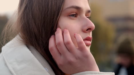 Close-up-shot-of-Caucasian-girl-in-down-jacket-dreamily-looking-away-on-city-view.