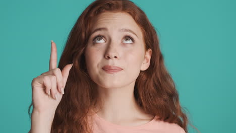Redheaded-girl-in-front-of-camera-on-turquoise-background.