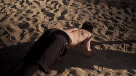 Conceptual-shot-of-young-muscular-man-doing-hard-exercises-during-functional-training-on-beach