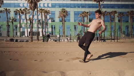 Young-handsome-muscular-man-doing-somersault-or-side-flip-on-city-beach