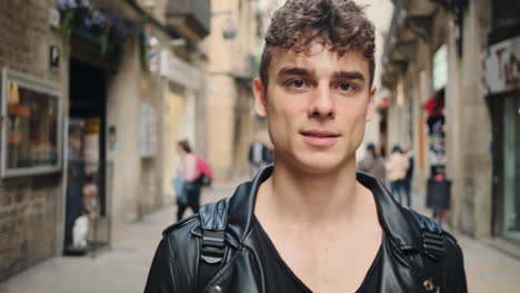 Tracking-shot-of-young-handsome-man-confidently-looking-in-camera-during-walk-through-city-street