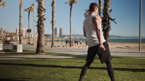 Tracking-shot-of-young-fit-man-doing-somersault-or-side-flip-during-workout-in-city-park