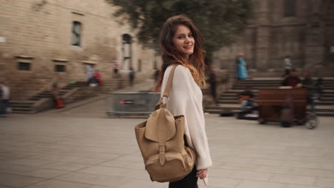 Young-woman-with-backpack-in-the-middle-of-old-big-square