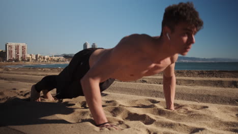 Joven-Atractivo-Musculoso-Haciendo-Flexiones-Durante-Un-Entrenamiento-Funcional-Junto-Al-Mar