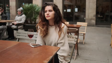 Young-girl-thoughfully-looking-something-sitting-in-outdoor-cafe