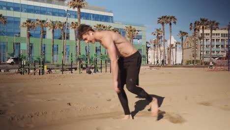 Joven-Deportista-Musculoso-Haciendo-Volteretas-O-Volteretas-Laterales-Durante-Un-Entrenamiento-Funcional-En-La-Playa-De-La-Ciudad