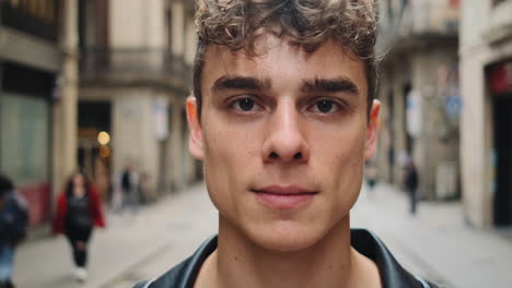 Tracking-shot-of-young-attractive-man-confidently-looking-in-camera-on-city-street