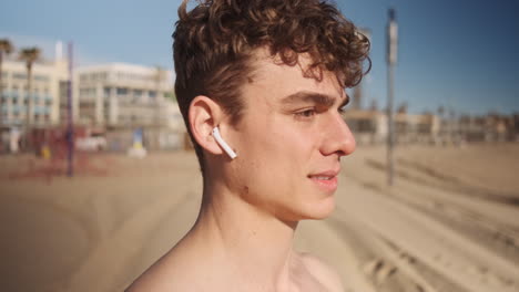 Close-up-shot-of-young-sporty-man-confidently-looking-in-camera-after-workout-on-beach