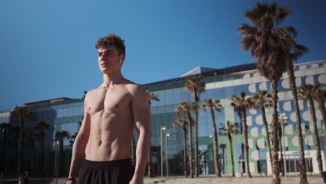 Tracking-in-shot-of-attractive-fit-guy-resting-after-workout-outdoor